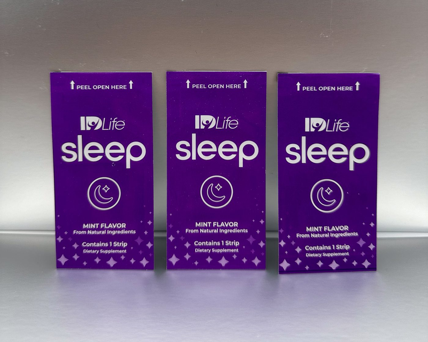 Three purple IDLife Sleep strip packs standing side by side, each printed Mint flavor, contains 1 strip