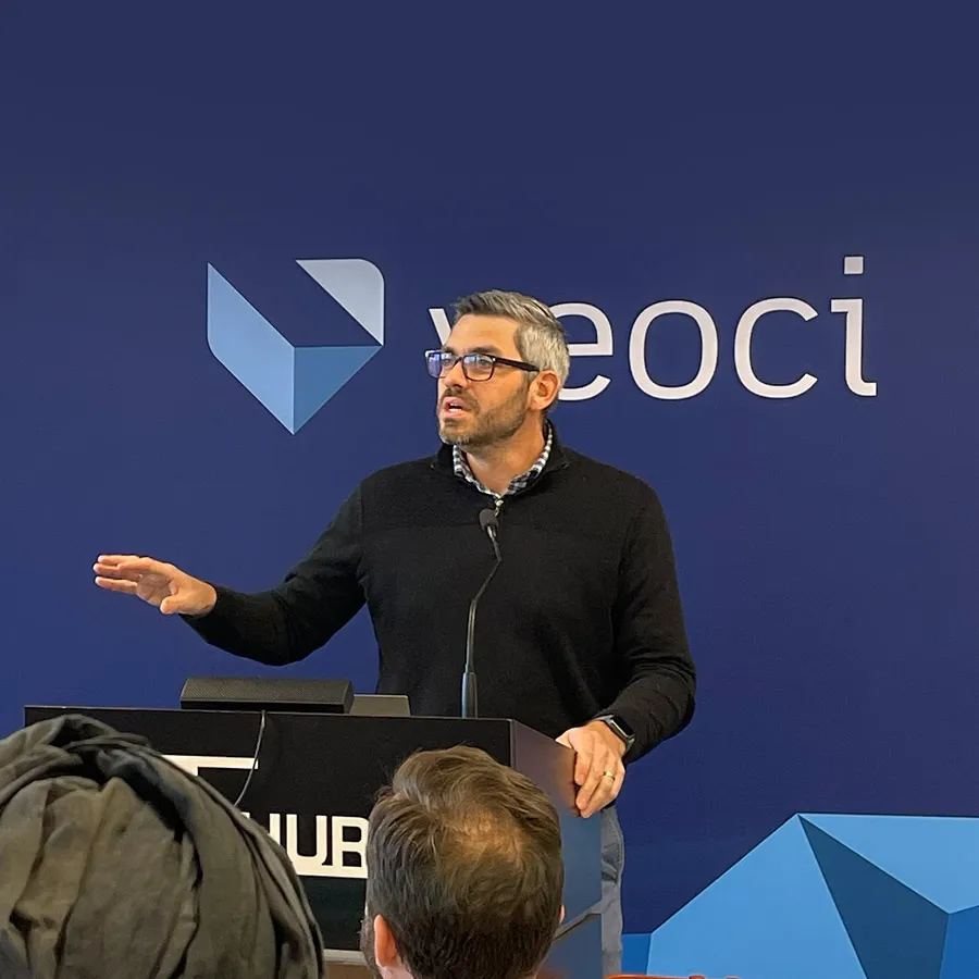 Speaker at a podium in front of a Veoci banner.