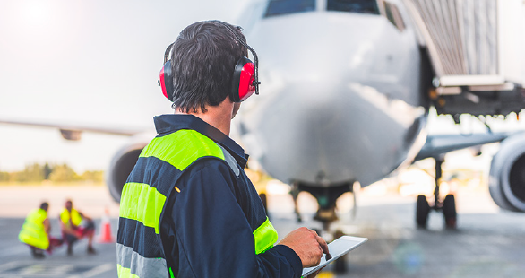 Airfield staff inspects an aircraft docked at a terminal gate.