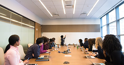 A speaker presents information to a group of people in a conference room.