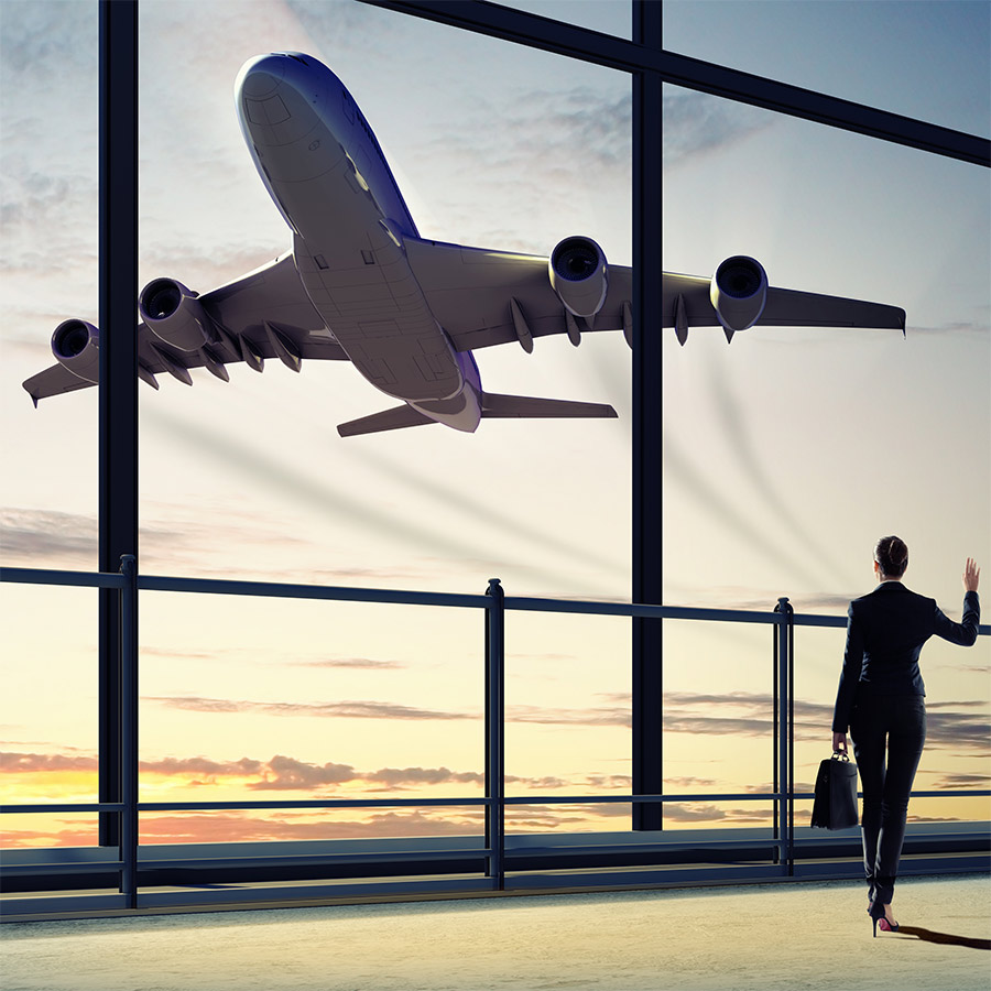 A person views a airplane taking off from a large window in the airport terminal.