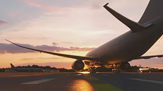 An aircraft moves through runways and taxiways on an airfield at sunset.