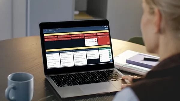A school district employee reviews operations metrics in Veoci on a laptop.