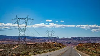A row of power line pylons streching through desert.