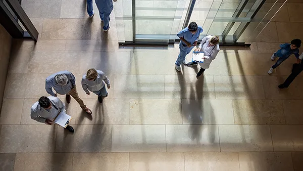 Medical staff walk through a busy lobby in a healthcare facility.