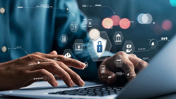 A person using a laptop, with icons showing connections and secure data practices above their hands on the keyboard.