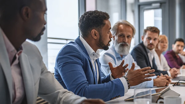 Executives and team members discuss topics during a meeting in a conference room.