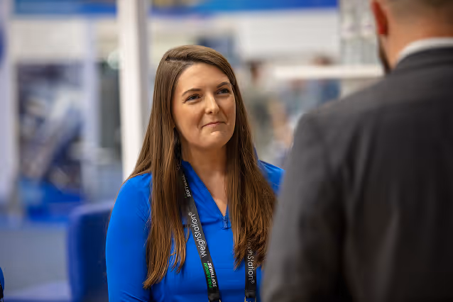 Waste Harmonics Keter employee in a branded polo speaking with an attendee at a trade show