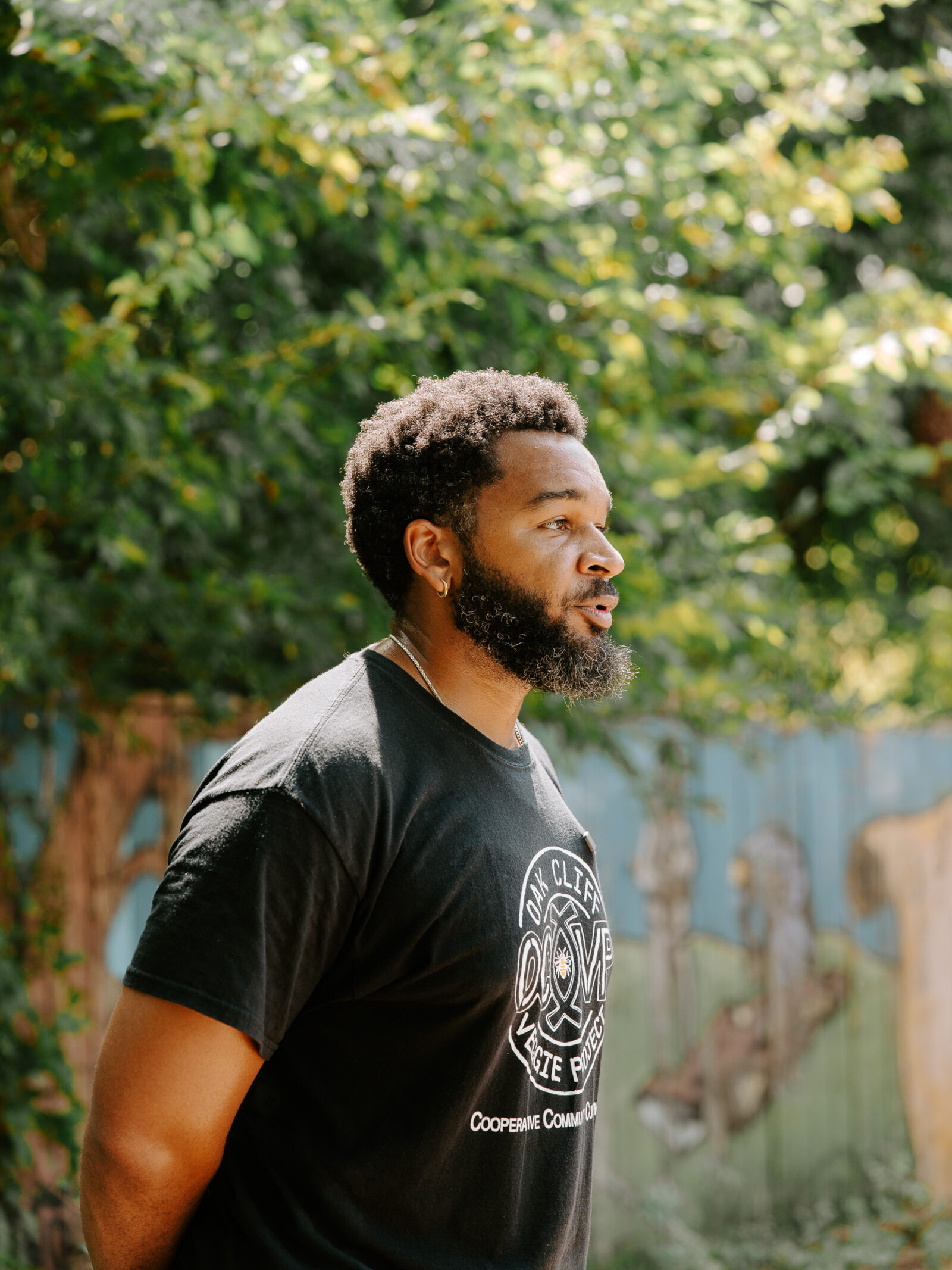 An Oak Cliff Veggie Project team member speaks on camera in front of the Tenth Street mural