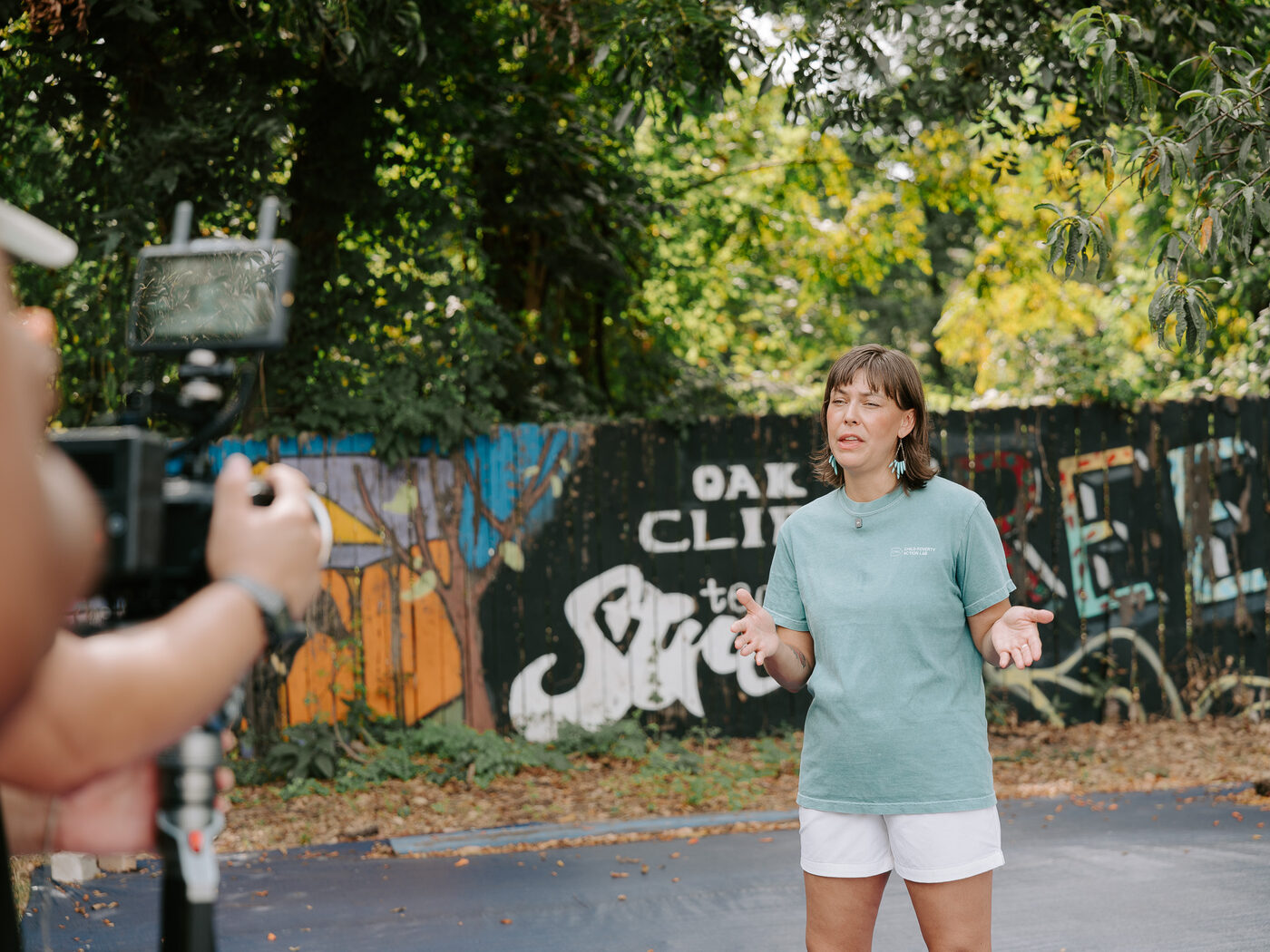 An interview subject stands in front of the Oak Cliff Freedman's Town mural during filming
