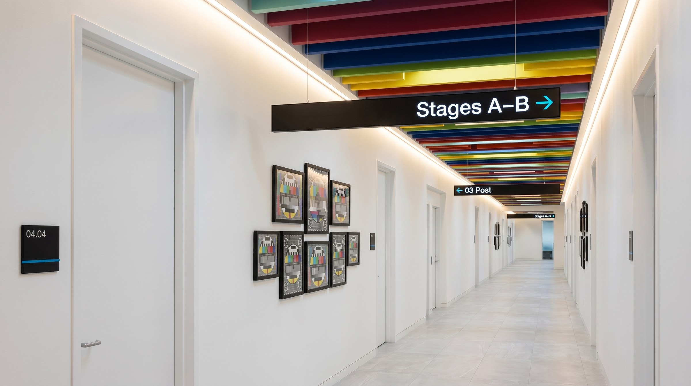 Corridor to Stages A and B at The Plex with a full signal-spectrum ceiling and overhead directional sign, environmental wayfinding by Good Word Agency