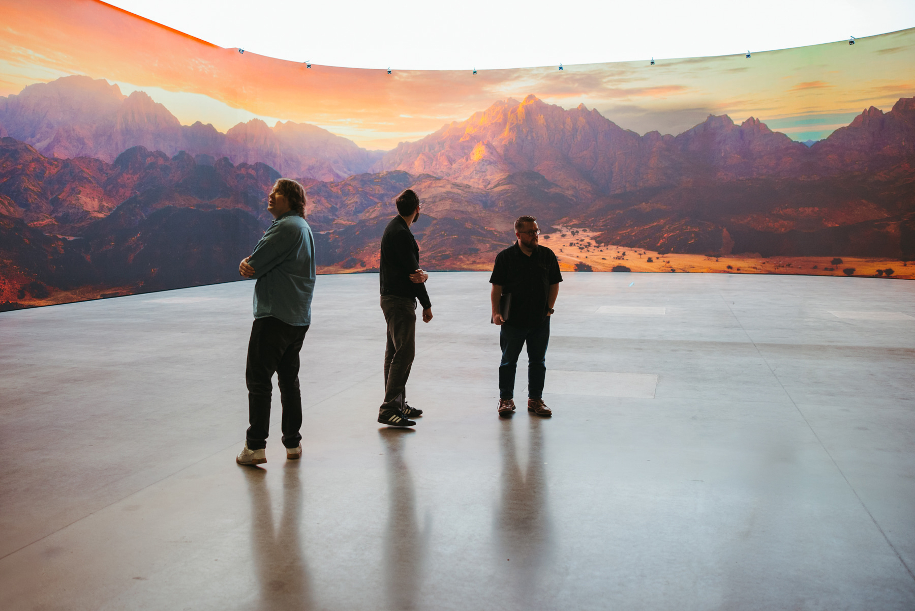 The Good Word Agency team standing inside the LED volume at The Plex in Fort Worth, Texas, with a mountain landscape running across the curved wall