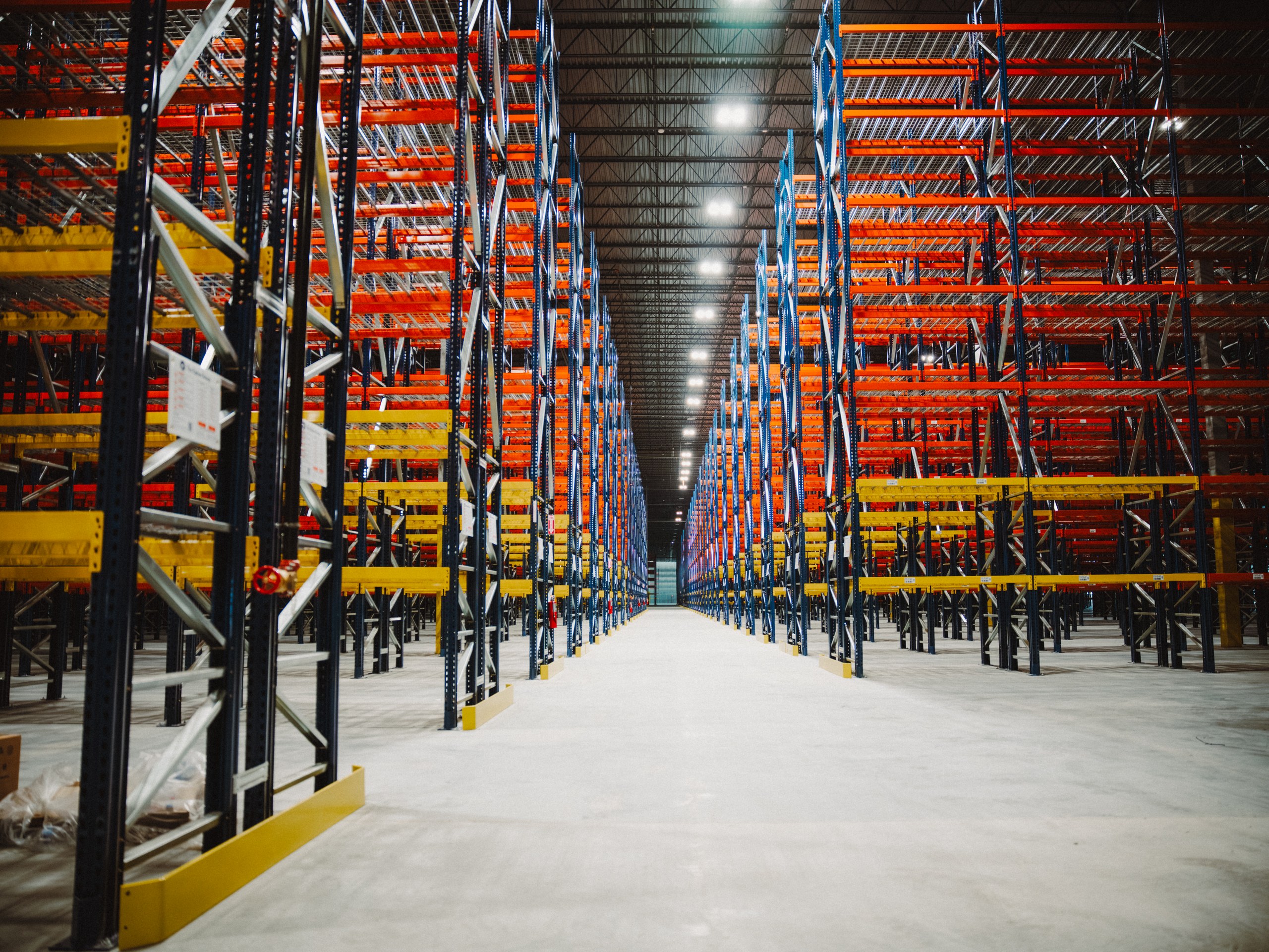 A finished warehouse racking aisle installed by The Optum Group, shot down the aisle to the back of the building