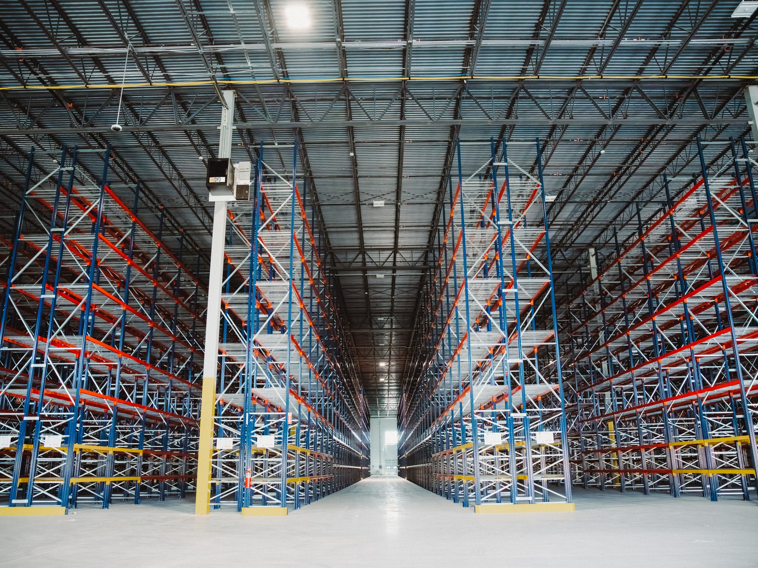 Warehouse racking installed by The Optum Group, two aisles converging toward the back of the building