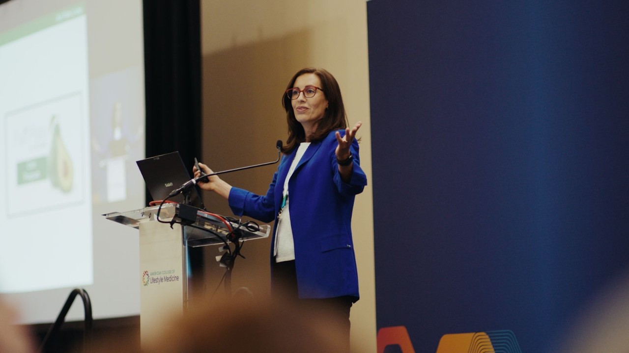A speaker presents from an American College of Lifestyle Medicine podium during a conference session