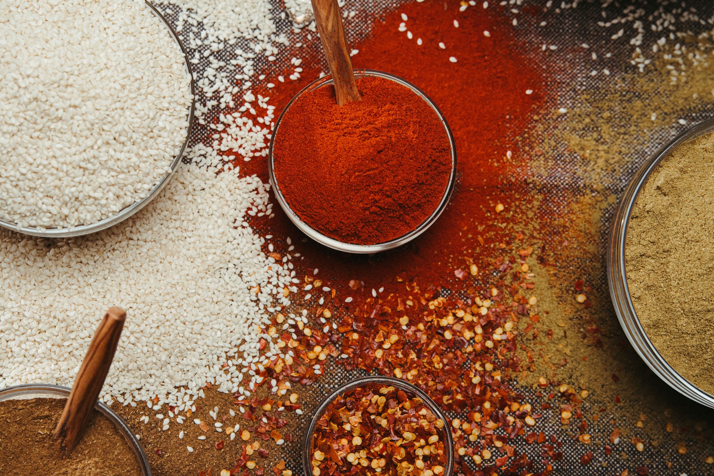 Bowls of 27 Peaks ground spices photographed from above, paprika, sesame and whole cinnamon