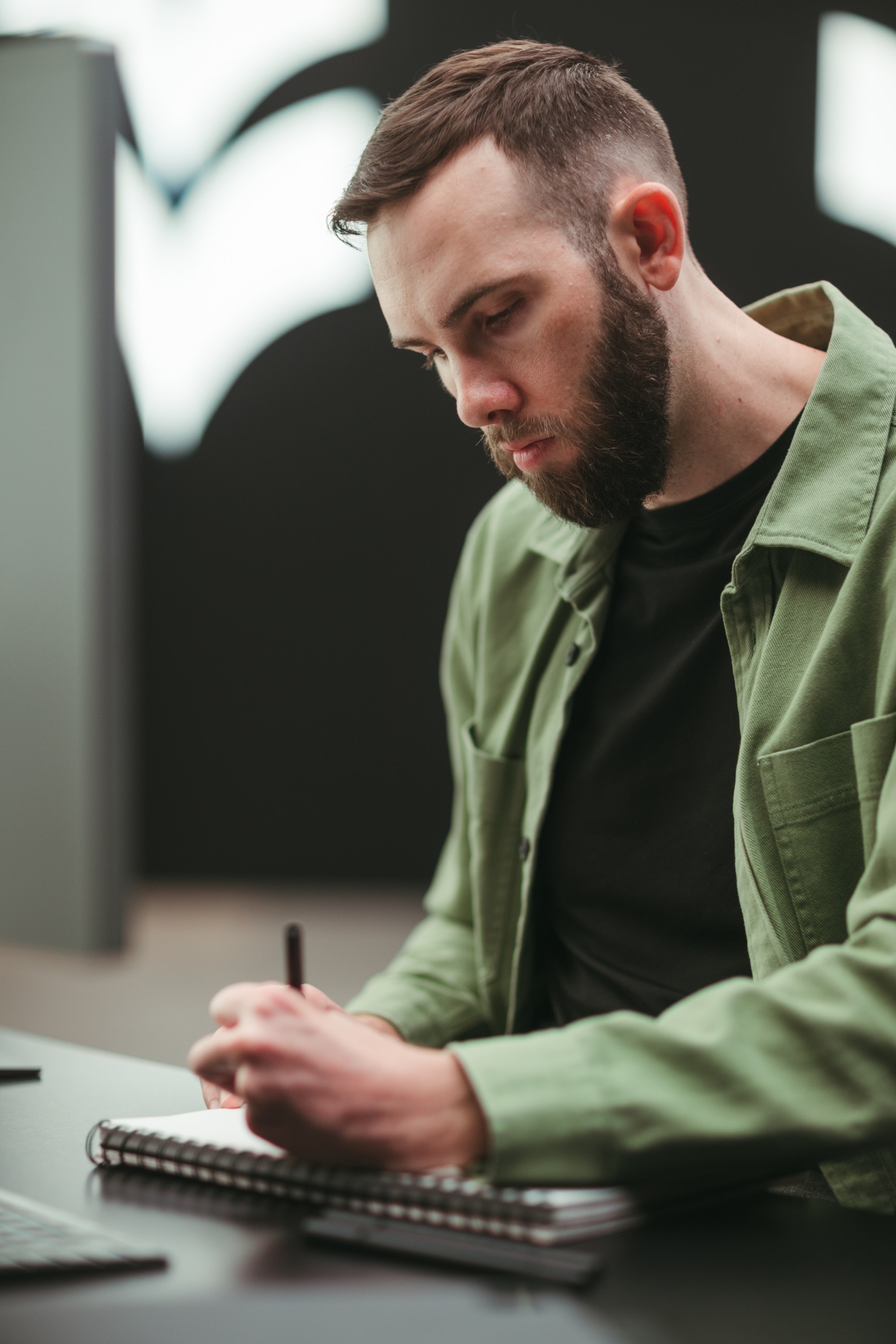 Subject writing in a notebook in a green jacket