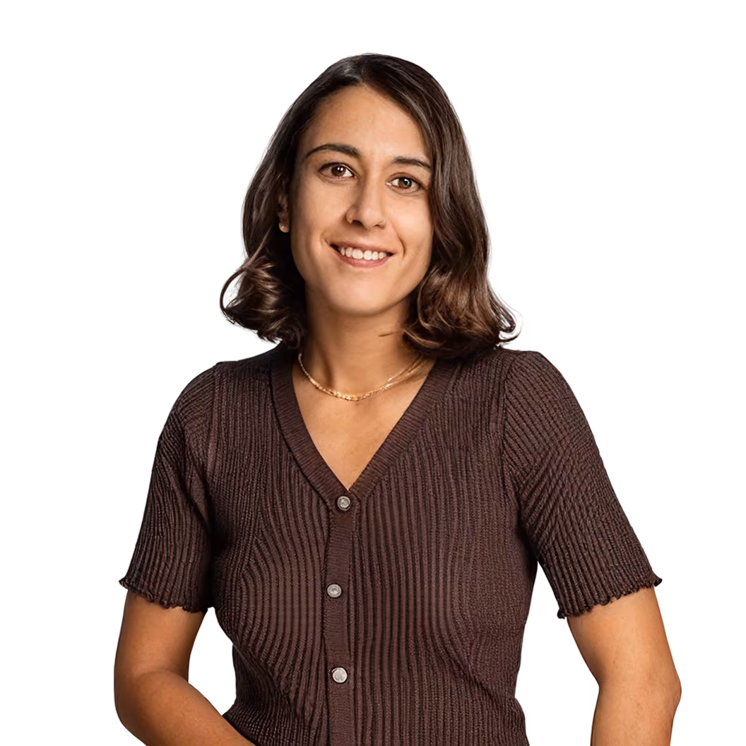 Headshot portrait of Joy Boublil smiling, wearing a brown cardigan against a teal background.