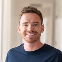 Portrait photo of a smiling man with a beard wearing a dark t-shirt.