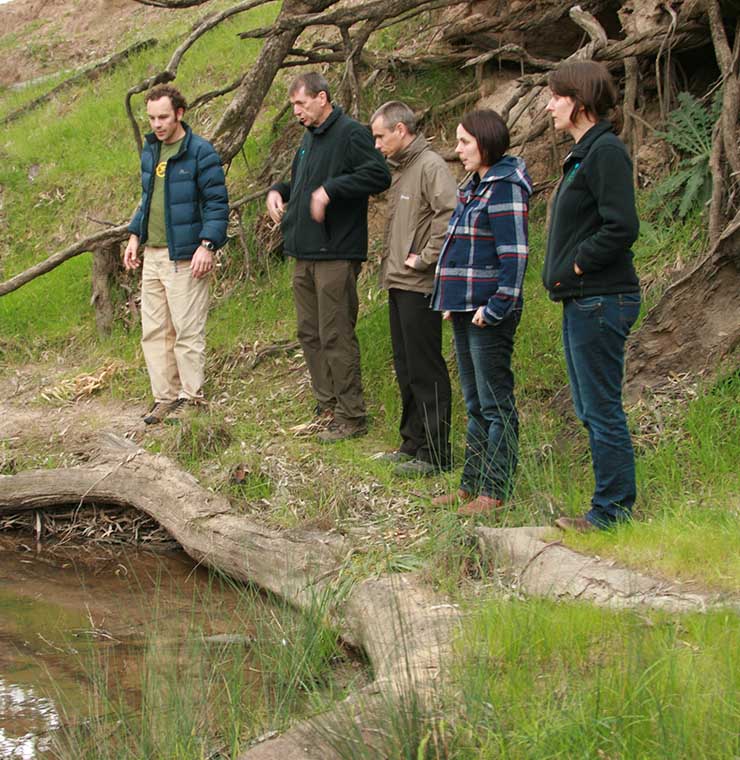 Environmental stakeholders and consultants conducting a field assessment along a riverbank