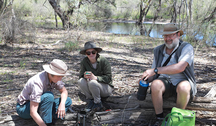 Field researchers taking a break near a riverbank during freshwater ecology field survey