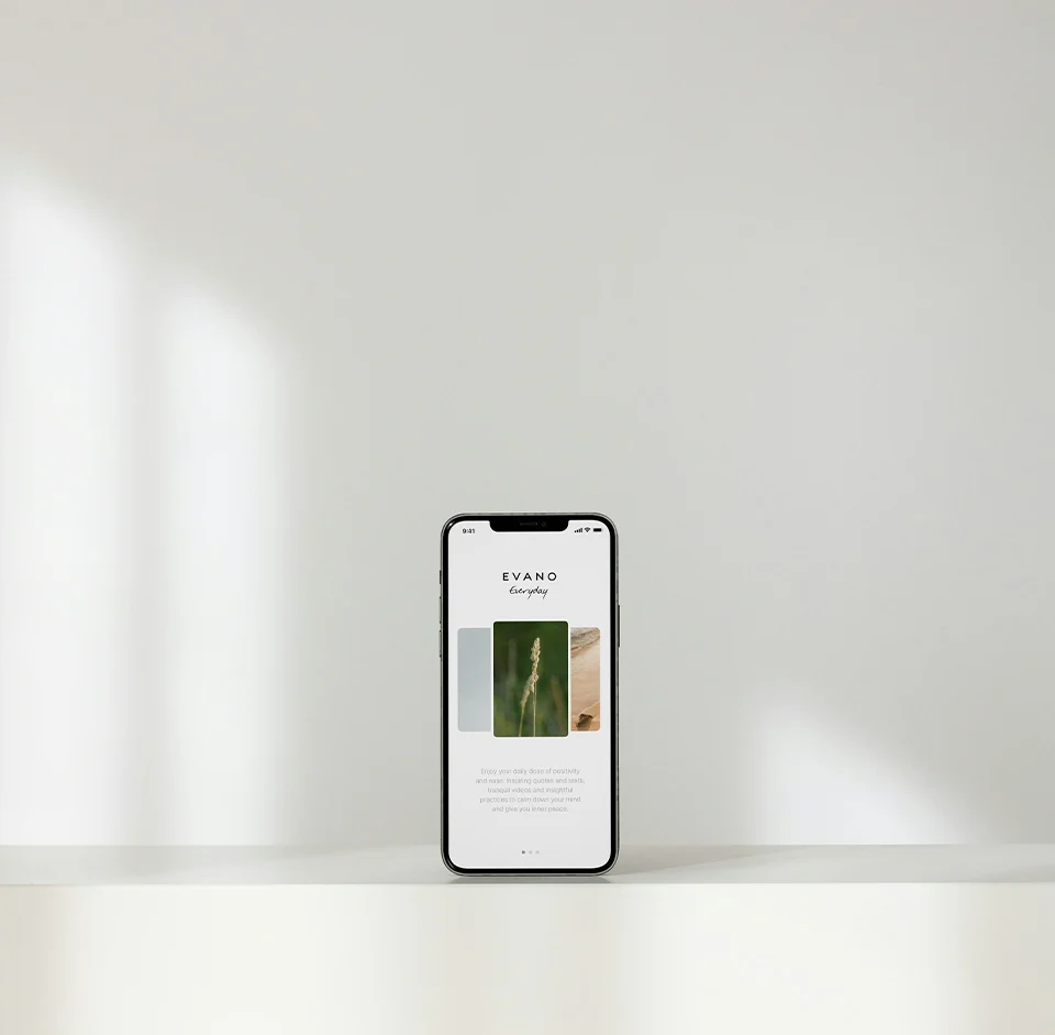 Smartphone on flat surface showing Evano Everyday app with nature images and text.
