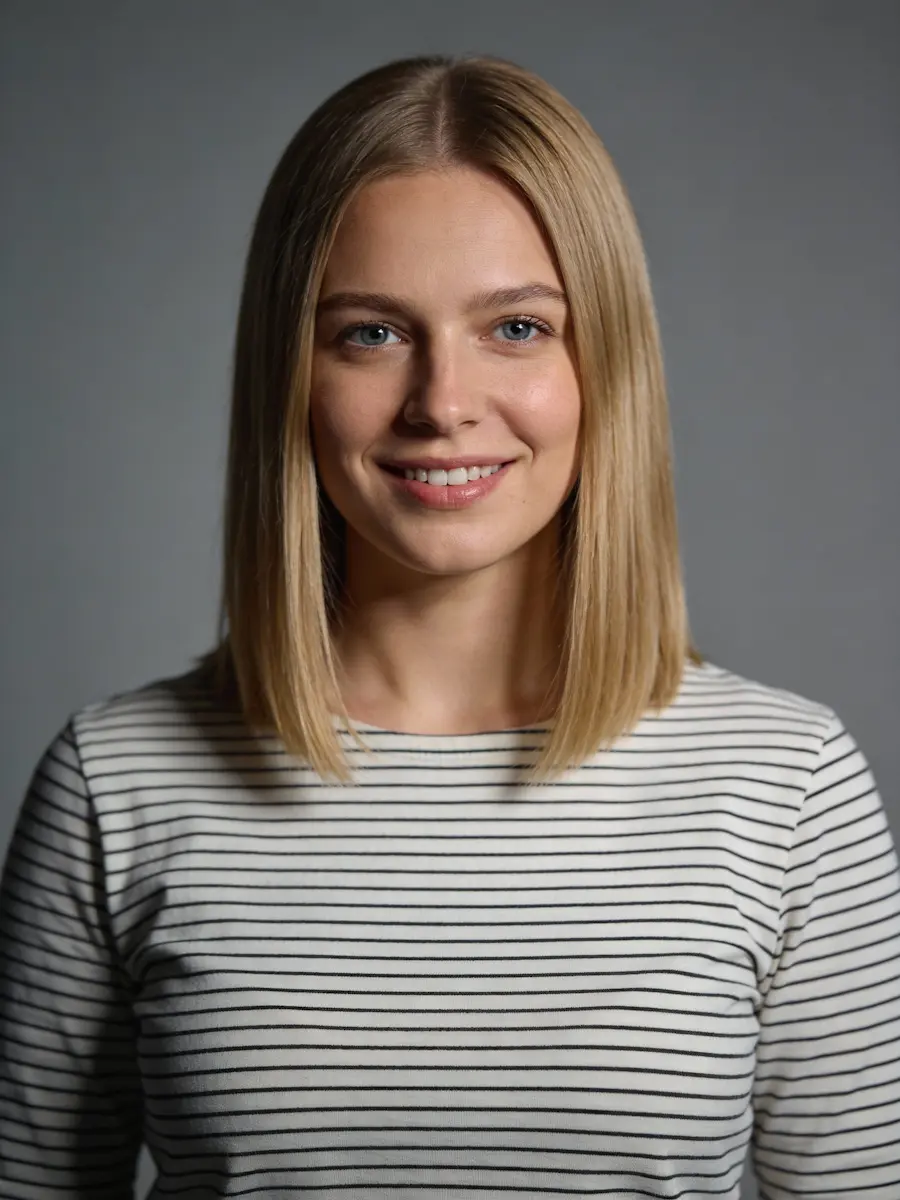 Smiling woman with straight blonde hair wearing a white and black striped shirt against a gray background.