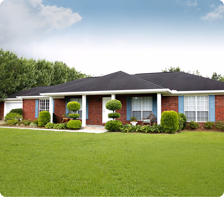 Single-story brick house with black roof, white door, blue window shutters, and manicured front yard.