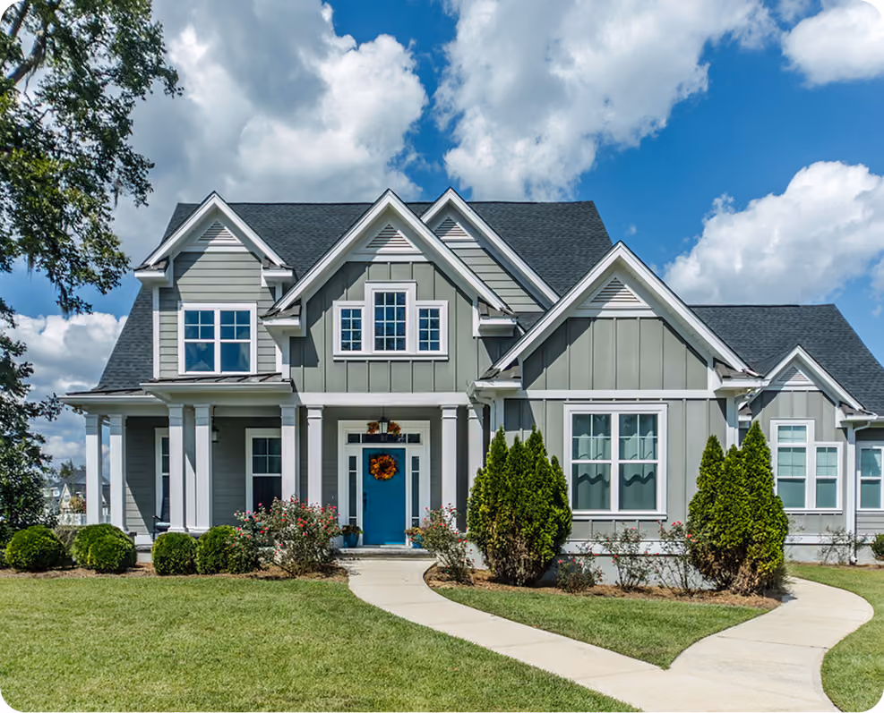 Gray two-story house with a bright blue door and symmetrical front lawn with curved sidewalks.