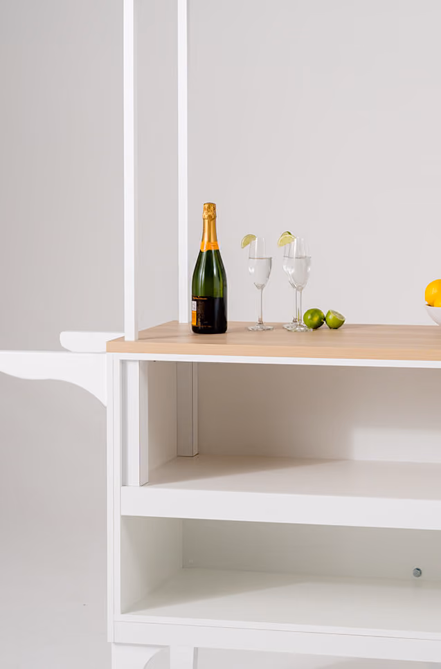 Bottle of champagne and two glasses with lime wedges on a wooden table surface.