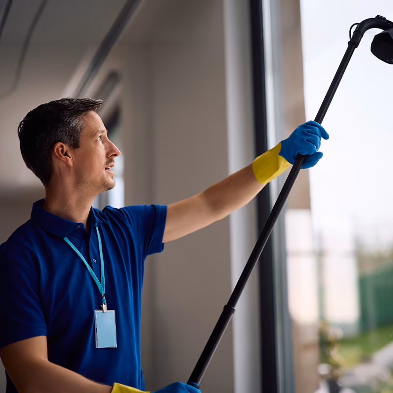 Fensterreinigung: Reinigungskraft zieht eine Fensterscheibe mit dem Abzieher ab