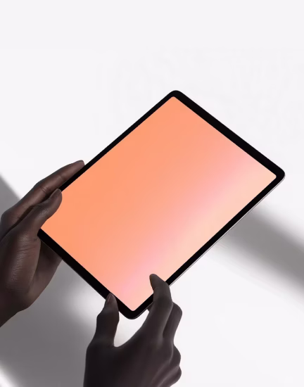 Hands holding a tablet with a blank, orange screen against a light background.