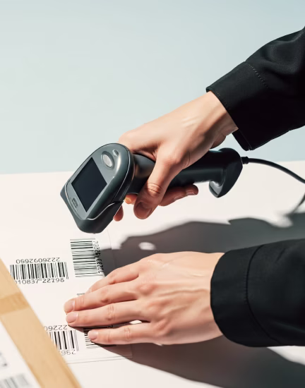 Person using handheld barcode scanner to scan codes on a package label.