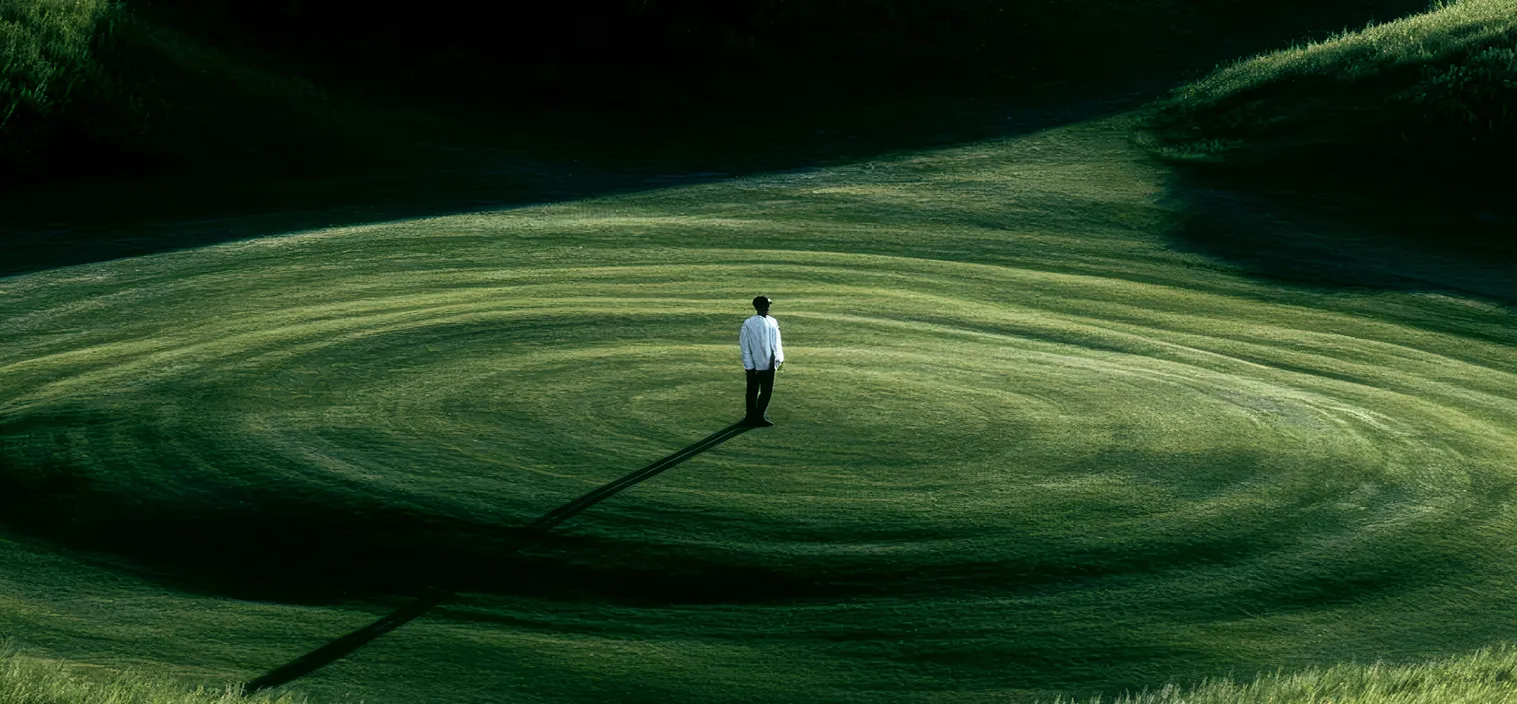 A lone figure standing on a sweeping green field, representing a business navigating a changed search landscape