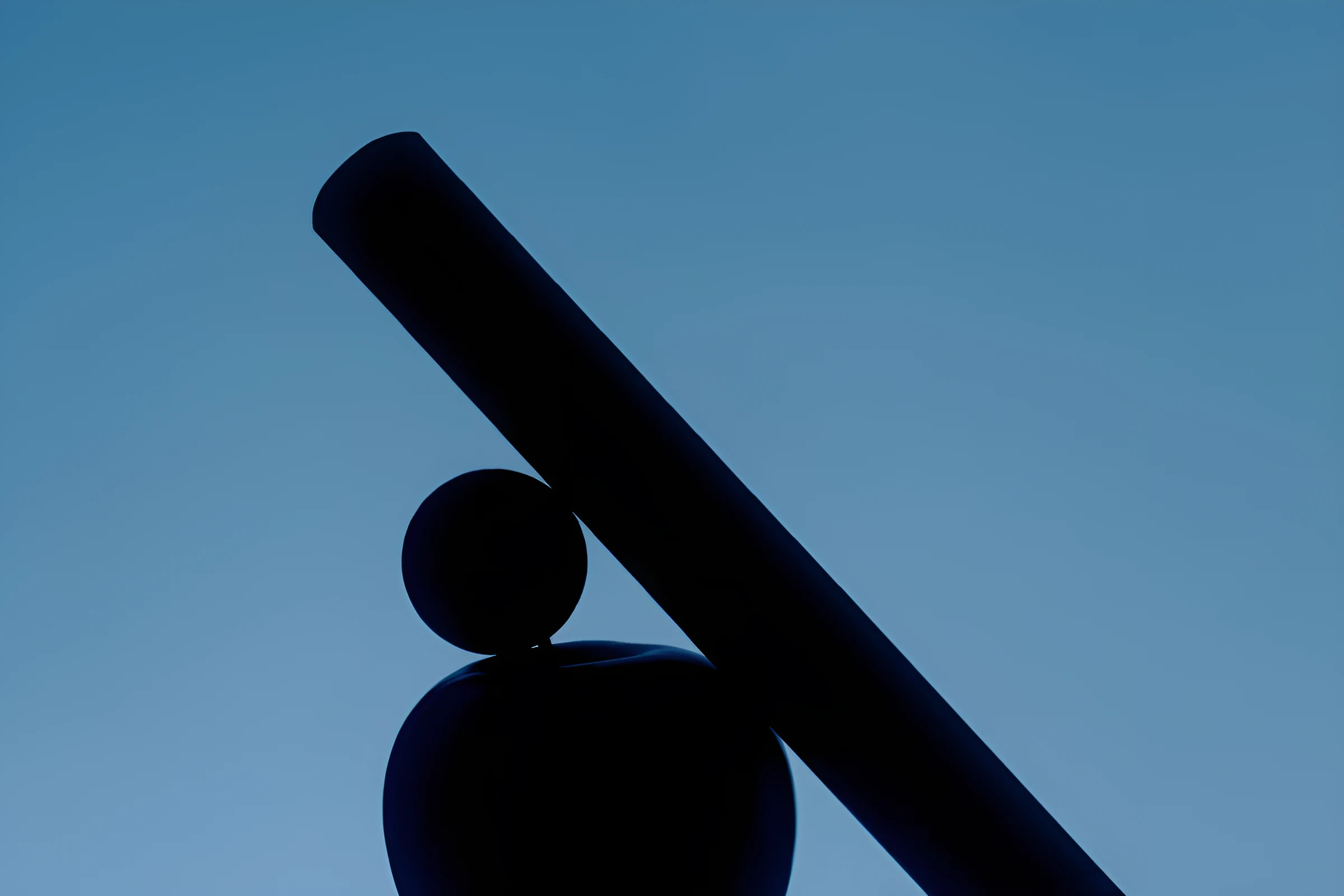 A dark bar balanced on a sphere against a blue sky, representing balance between automation and oversight