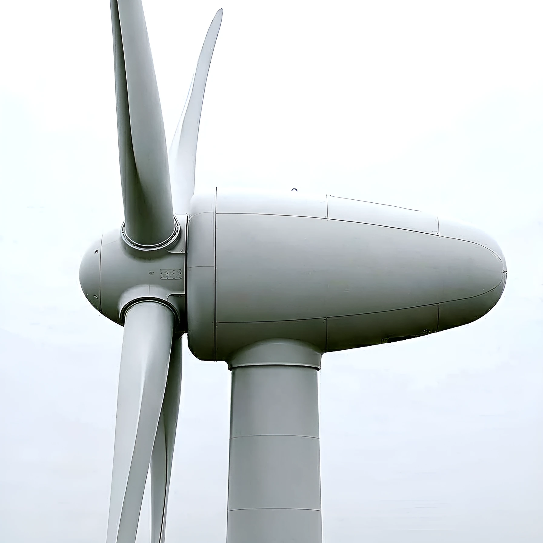 Wind turbine nacelle and blades against a pale sky
