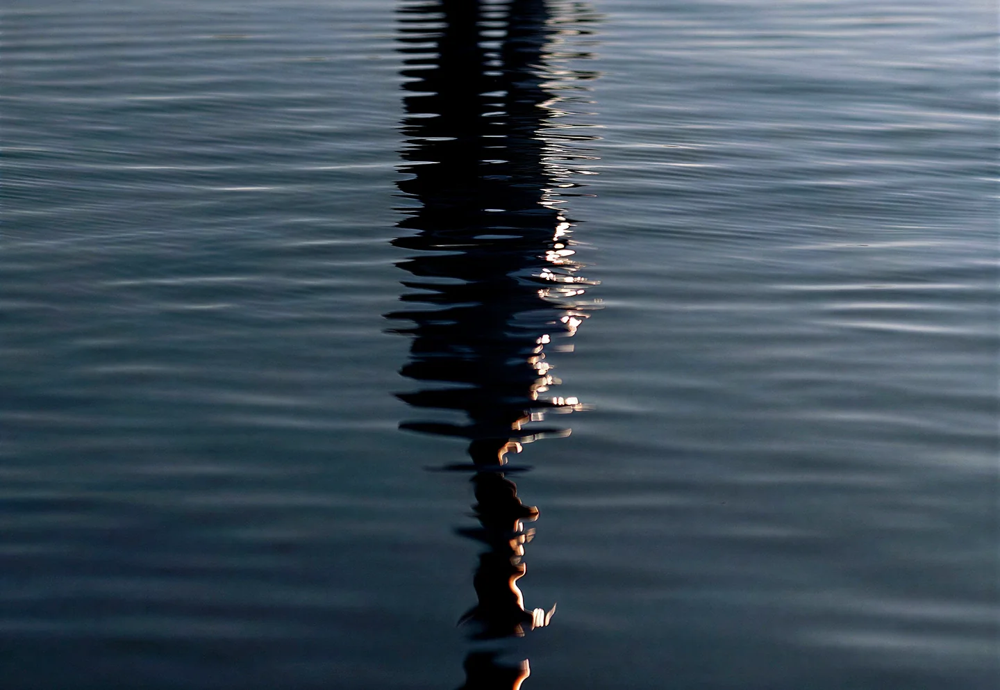 A figure reflected in still, dark water