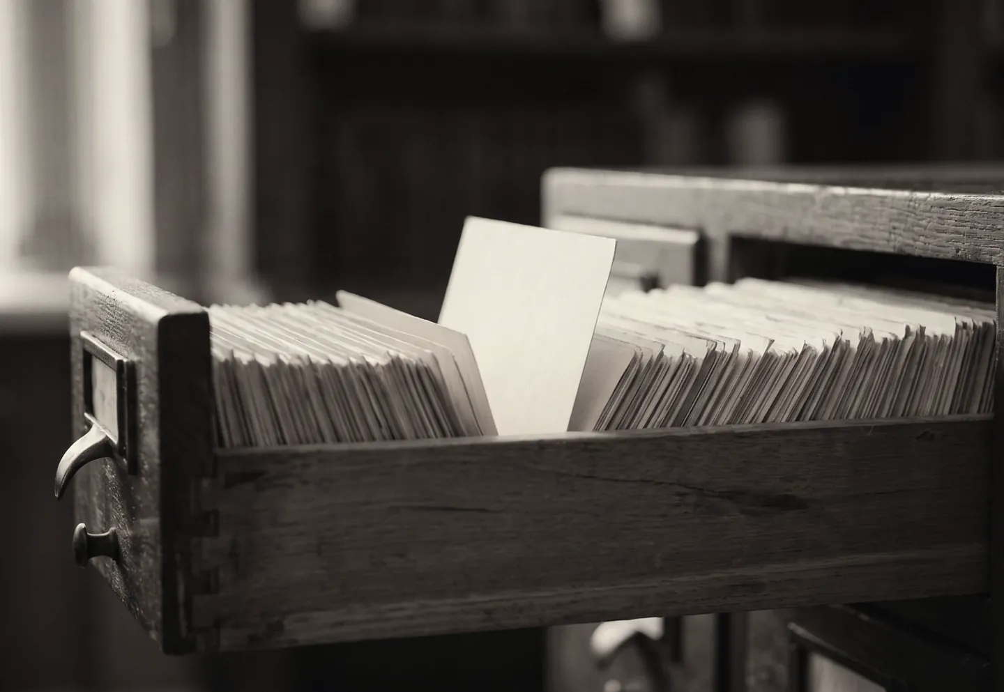 An open library card drawer with one blank card raised above the rest