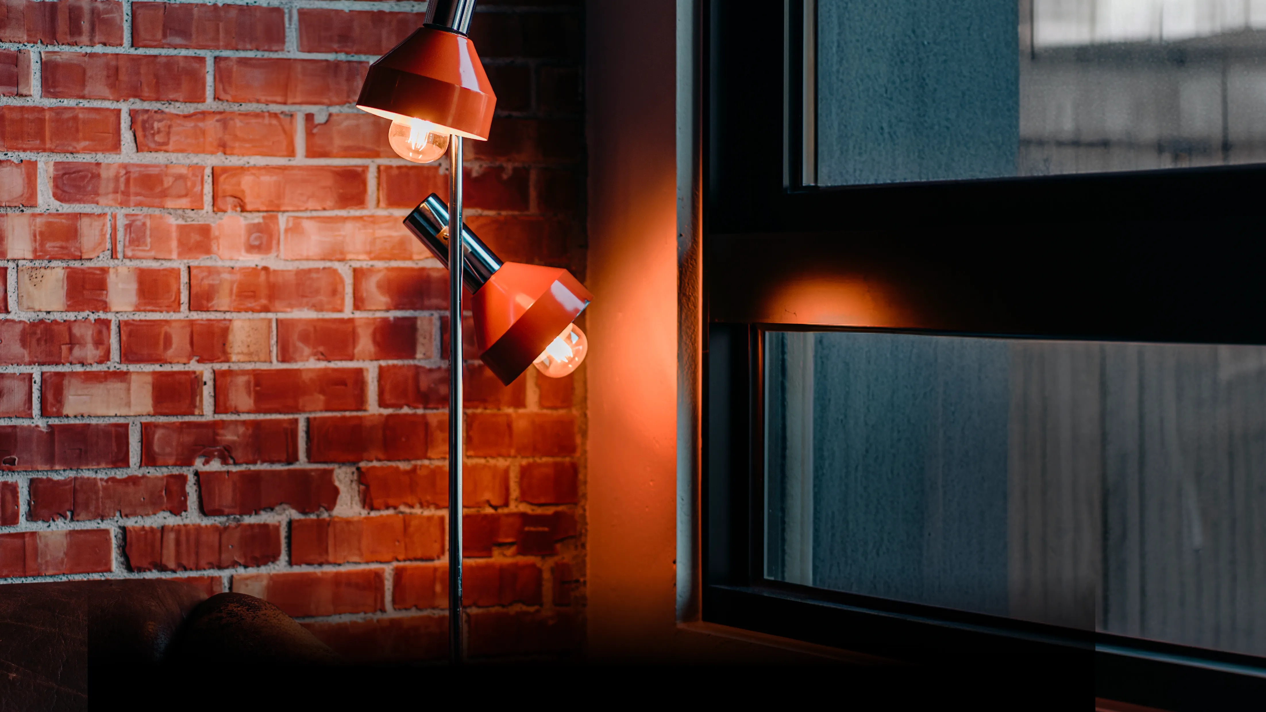 Warm orange lamps glowing against exposed brick wall, Ampersand lifestyle hotel interior