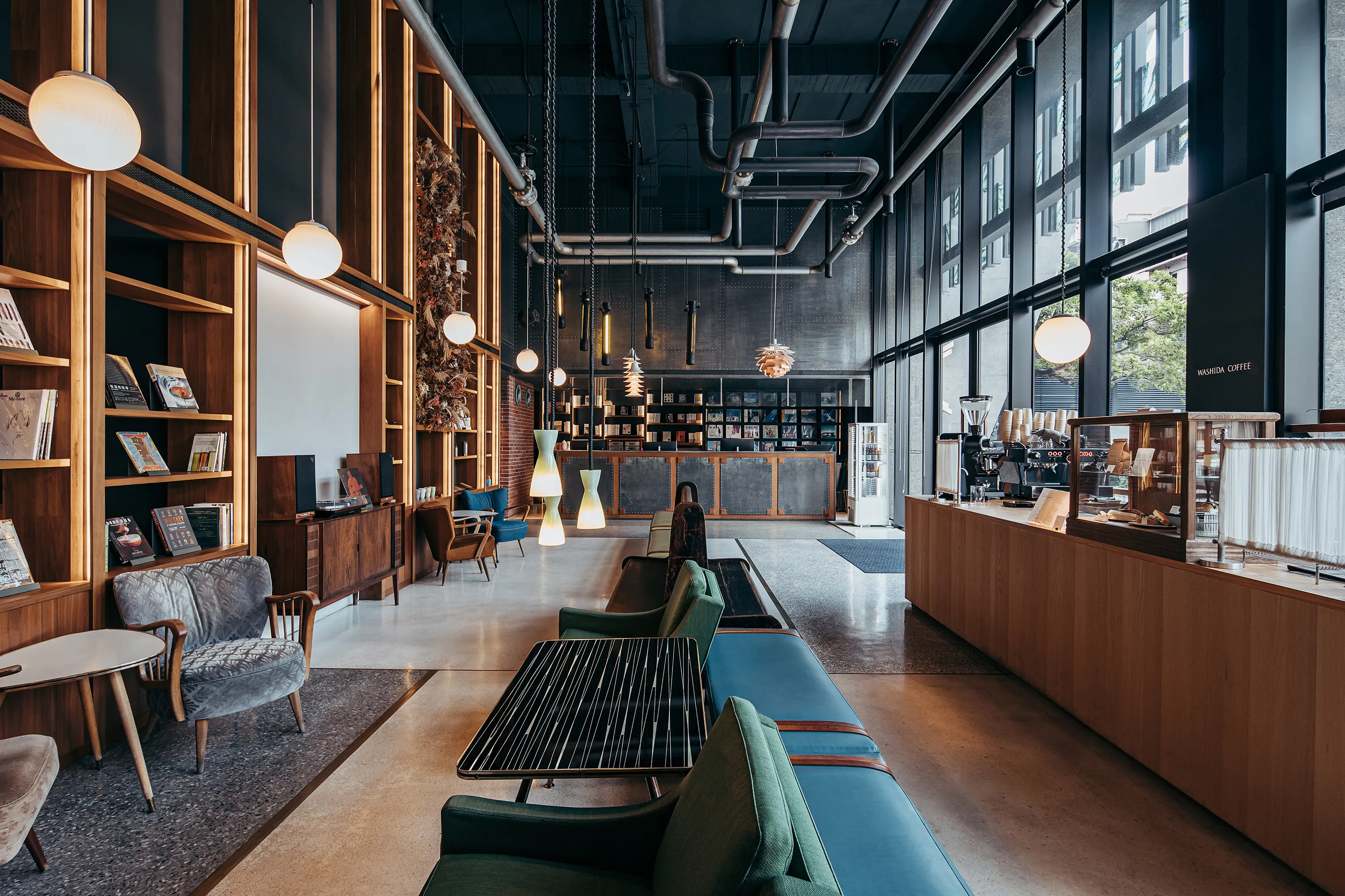 U.I.J hostel lobby in Tainan lit by natural light, with vintage furniture, wooden bookshelves, and Washida Coffee counter