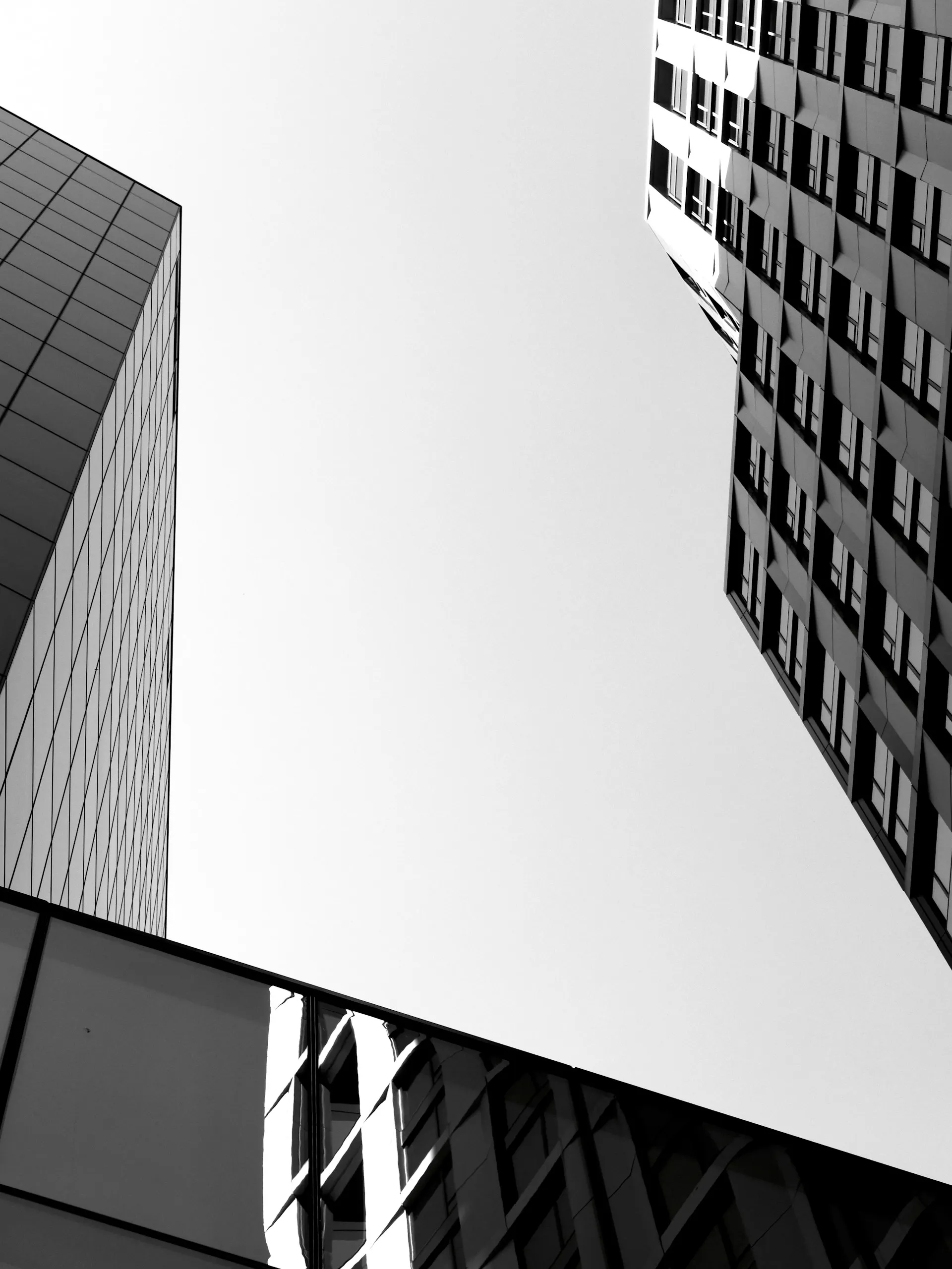 Black-and-white upward view of glass office towers with converging architectural lines