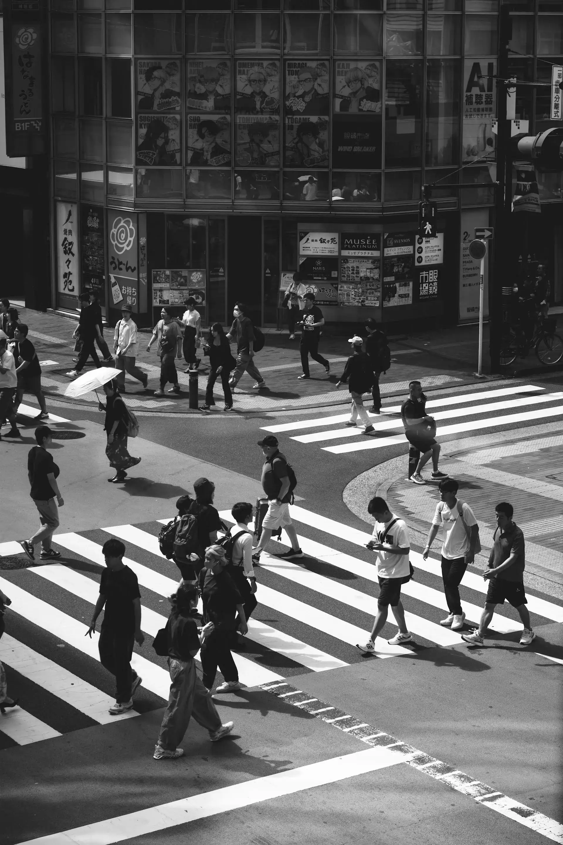 Black-and-white street photo of pedestrians crossing a busy Japanese city intersection
