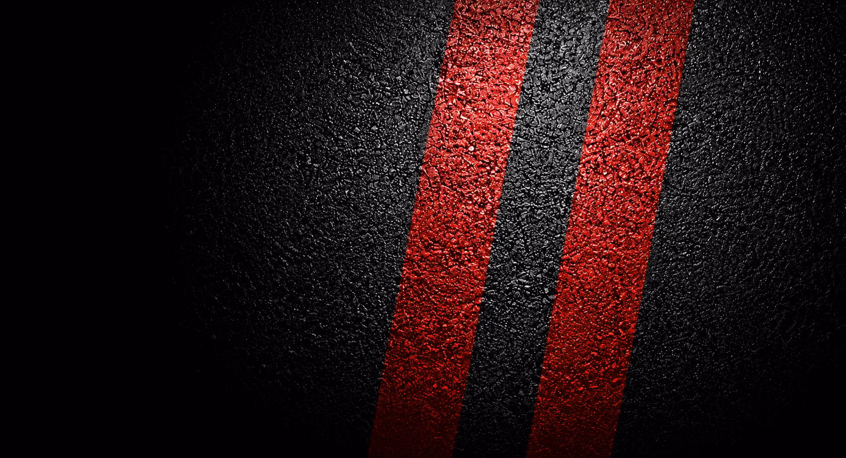 Close-up of a textured black asphalt surface with two parallel red painted stripes running vertically.