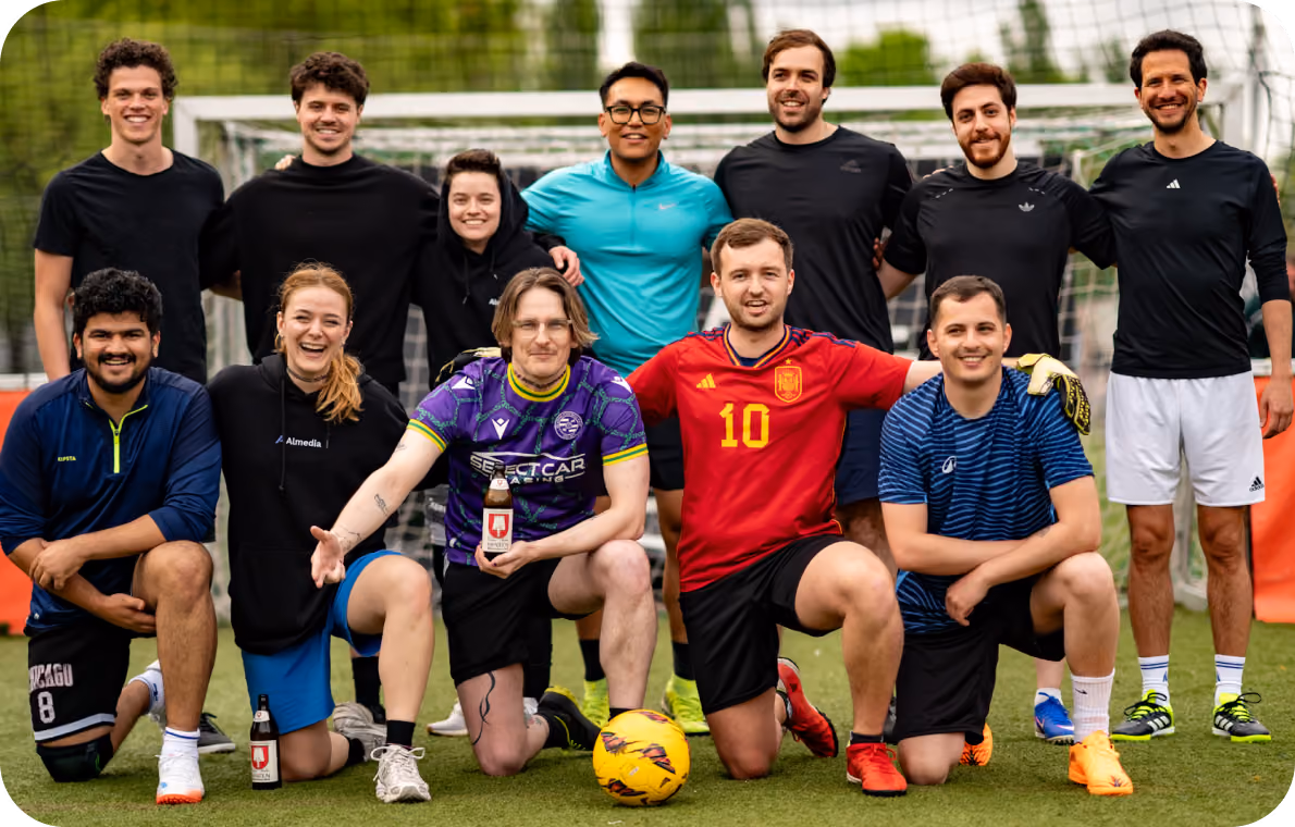 Almedia employees posing in football uniforms with a football