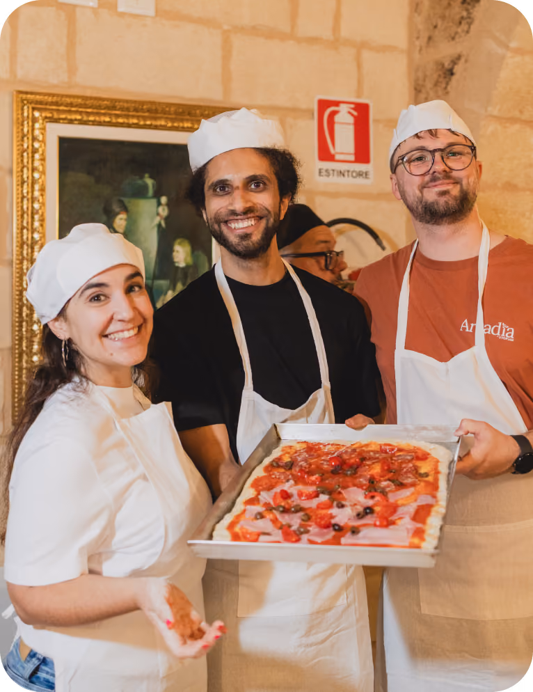 Almedia employees in baking uniforms holding a pan with food
