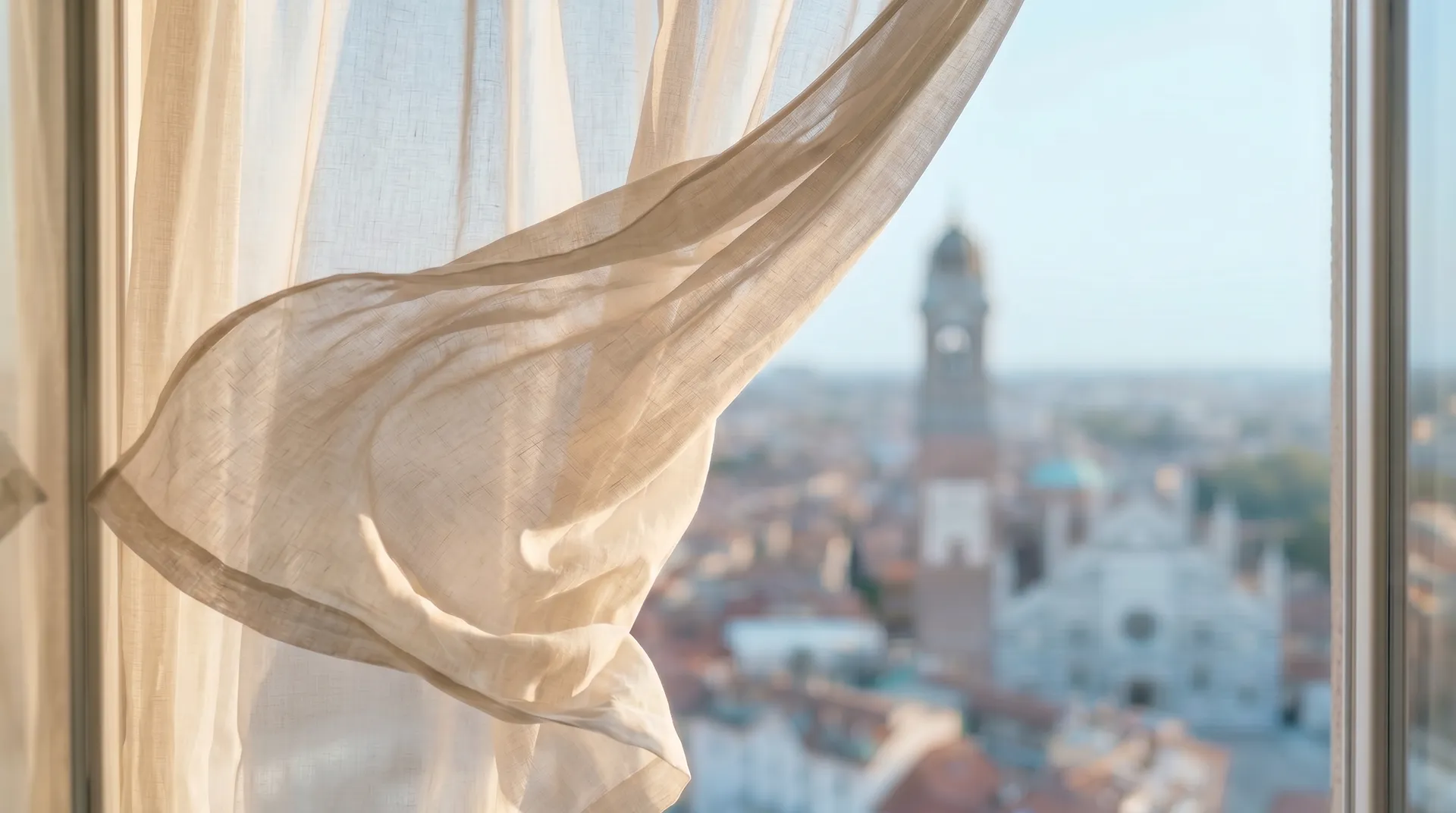 Tenda in lino chiaro davanti a una finestra con vista panoramica sui tetti e sugli edifici della città.