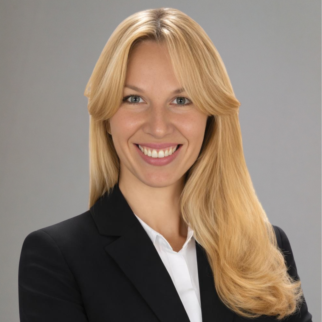 Portrait of a young woman with long blonde hair and glasses wearing a light blue shirt.