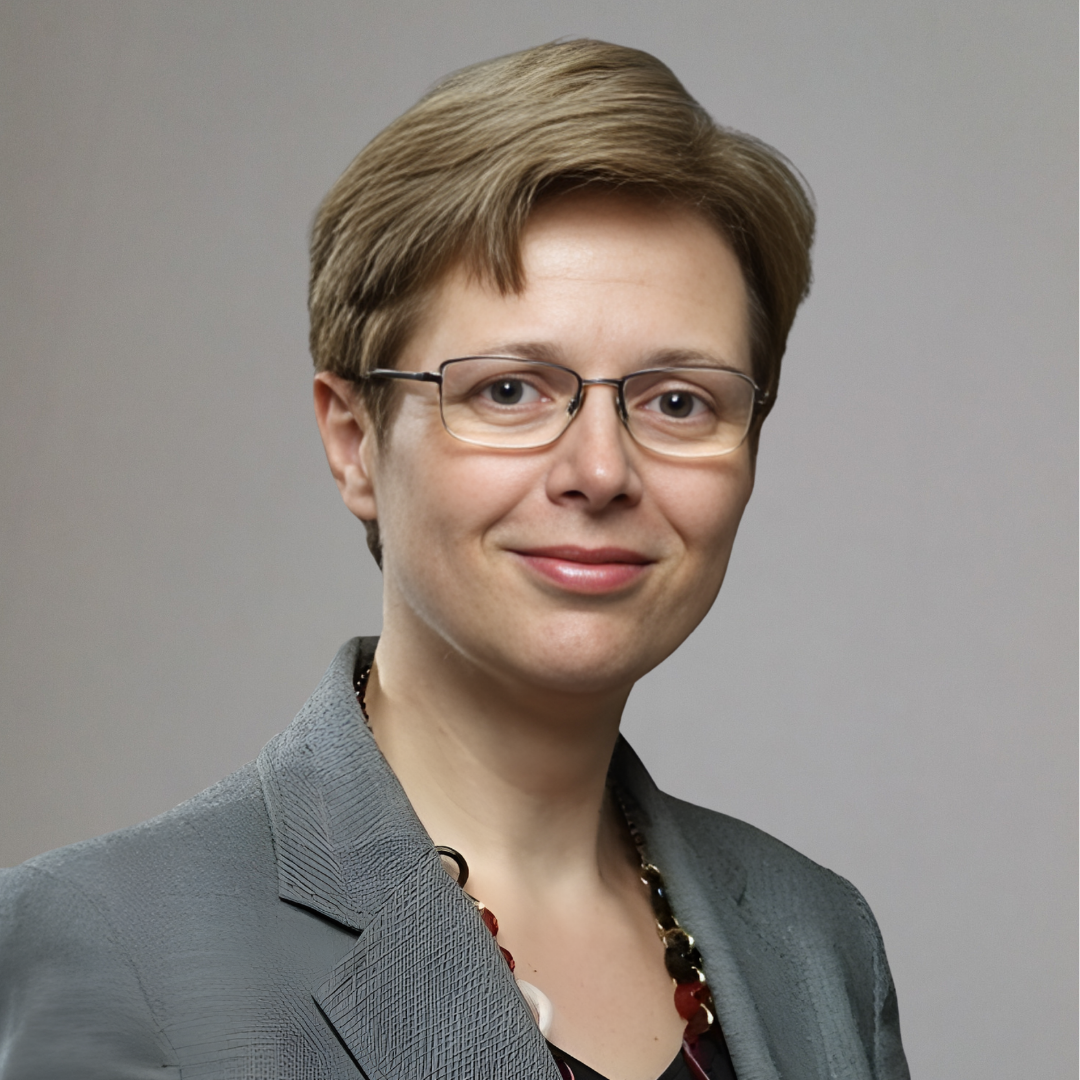 Portrait of a young woman with long blonde hair and glasses wearing a light blue shirt.