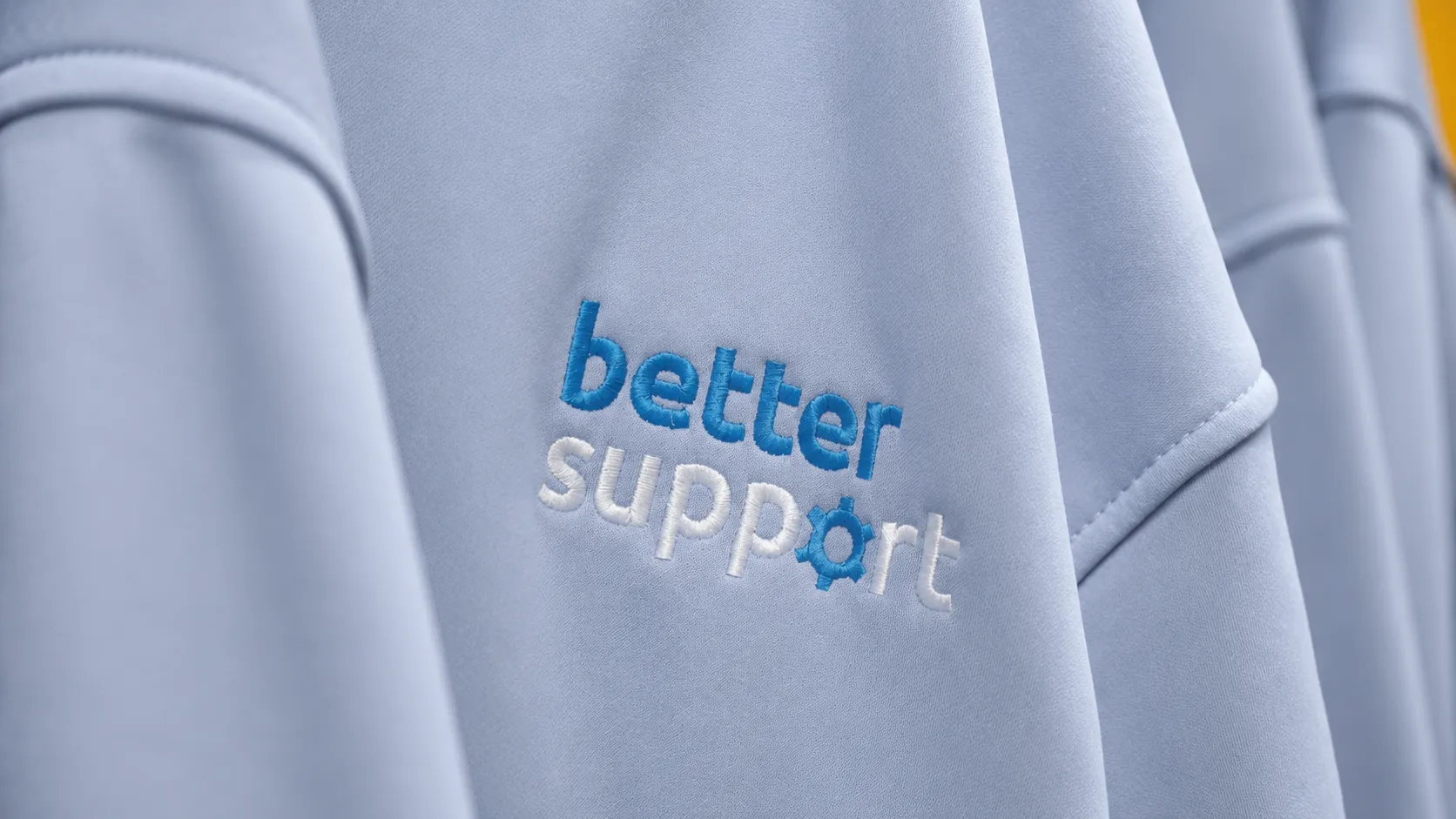 Light blue fabric with embroidered text 'better support' and a gear symbol replacing the letter o.