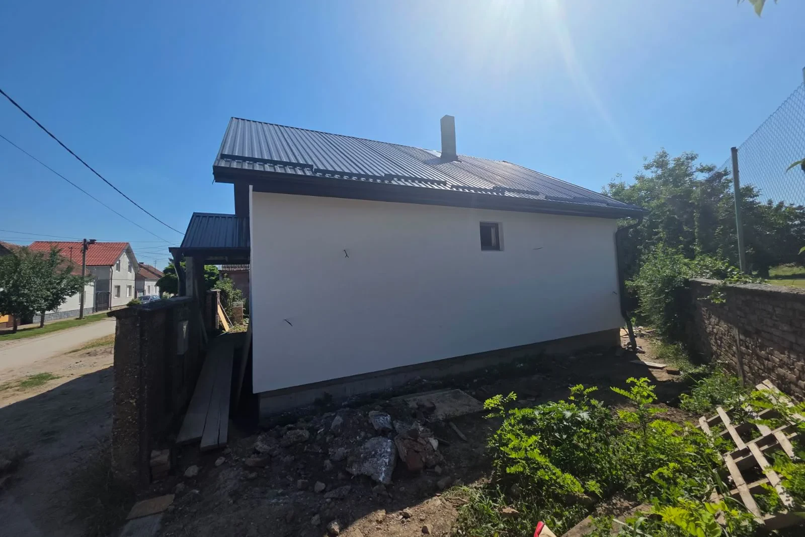 Montažna kuća u Sremskoj Mitrovici snimljena sa ulice, bela fasada i tamnosivi limeni krov završeni